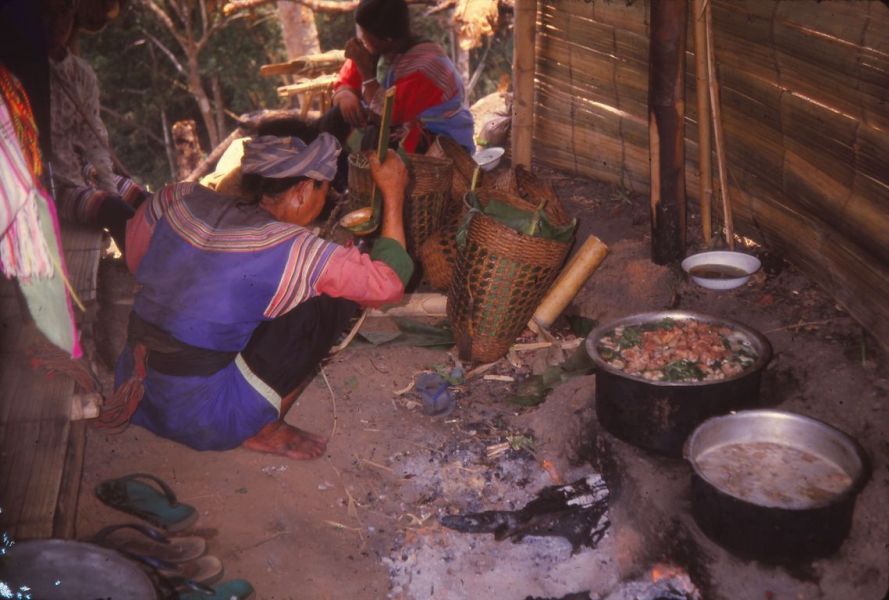 A Lisu grandmother is tasting the food in the field hut. The ladle is made of bamboo and one basket is filled with rice which was already cook from her home. EFEO_KLEO00144
